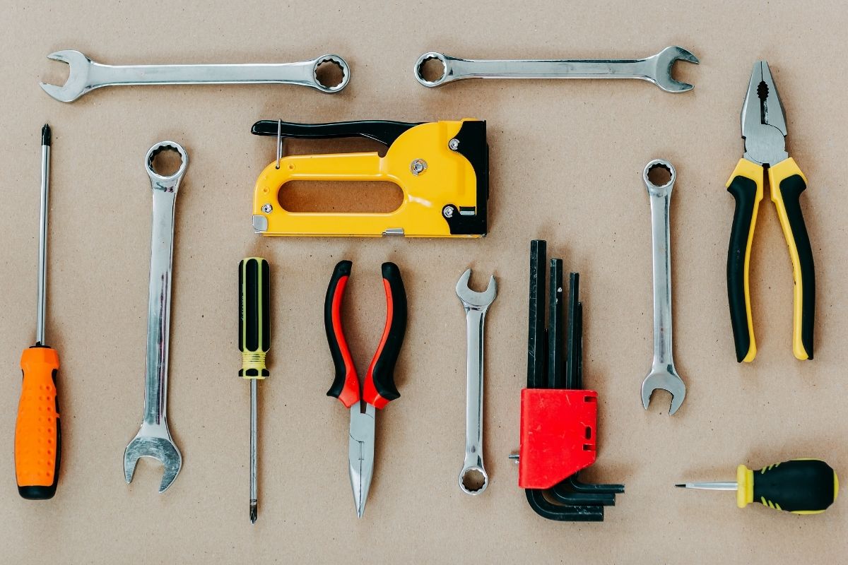 A collection of various tools arranged on a brown background, showcasing their shapes and colors.